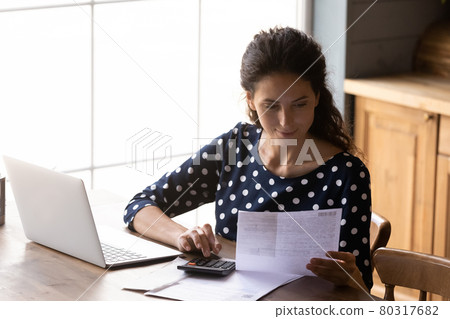 Focused young woman using calculating taxes, budget, costs, paying bill Focused young woman using calculating taxes, budget, costs, paying bill 80317682