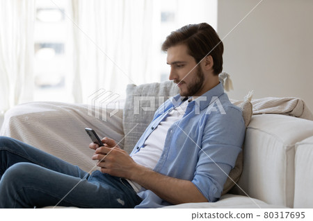 Focused engaged millennial young guy with mobile phone Focused engaged millennial young guy with mobile phone 80317695