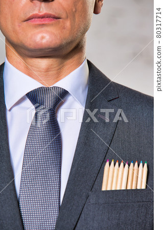 Businessman with colored pencils in pocket against wall 80317714