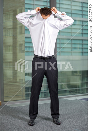 Businessman removing shirt at office 80317770