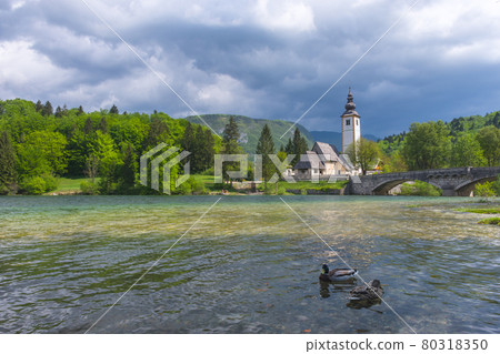The charming little Church of St. John the Baptist on lake Bohinj, Julian Alps, the largest permanent lake in Slovenia. Beautiful spring colors and dramatic sky 80318350