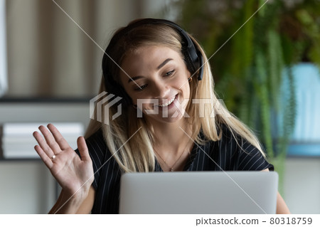 Close up businesswoman in headphones waving hand at laptop webcam 80318759