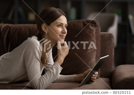 Dreamy young beautiful woman using digital computer tablet. 80320151
