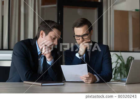 Two serious businessmen, focused business partners, coworkers reading document 80320243