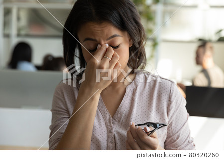 Tired mixed race Black business woman touching, rubbing nose bridge Tired mixed race Black business woman touching, rubbing nose bridge 80320260