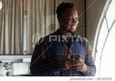 Smiling dreamy African American businessman distracted from smartphone in office 80320335