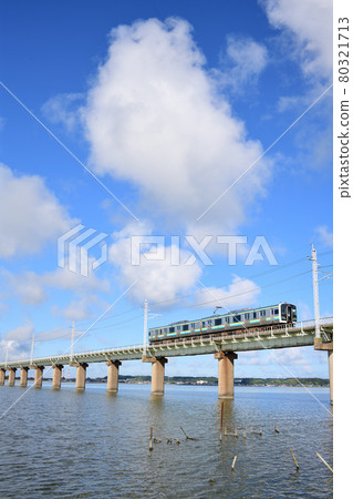 Kashima Line E131 series train crossing the cloudy Kitaura Bridge 80321713