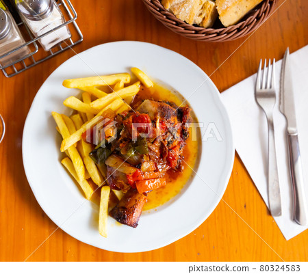 Tasty pork knuckle with potatoes and stewed peppers served 80324583