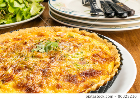High angle view of homemade bacon spinach quiche in black metal oven pie baking plate. High angle view of homemade bacon spinach quiche in black metal oven pie baking plate. 80325216