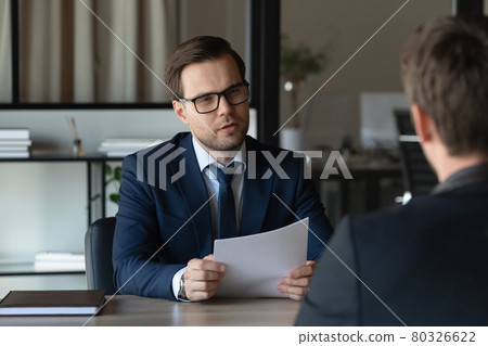 Serious concentrated employer with paper resume interviewing job candidate 80326622