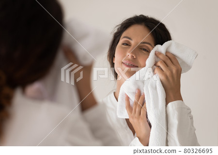 Smiling millennial female dry face with cotton towel after washing Smiling millennial female dry face with cotton towel after washing 80326695