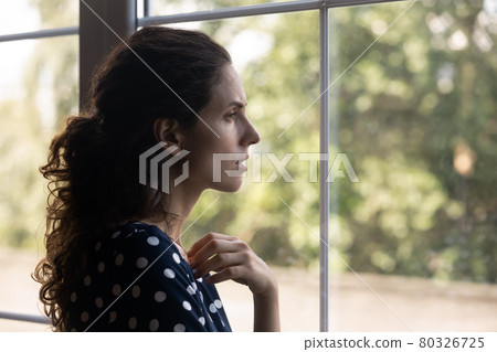 Frustrated depressed millennial woman looking out window Frustrated depressed millennial woman looking out window 80326725