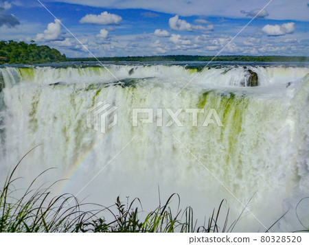 阿根廷-巴西邊境地區伊瓜蘇瀑布的彩虹般的魔鬼喉嚨和藍天 80328520
