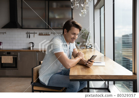 Happy young handsome man using smartphone in office kitchen. Happy young handsome man using smartphone in office kitchen. 80329357