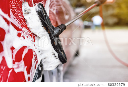 Red car washed in self serve carwash , detail on brush leaving strokes on side door Red car washed in self serve carwash , detail on brush leaving strokes on side door 80329679