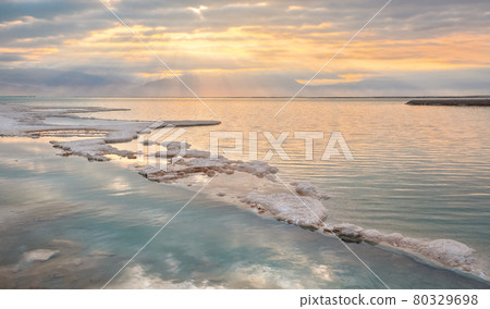 Morning sun shines on salt crystals formations, clear cyan green calm water near, typical landscape at Ein Bokek beach, Israel 80329698