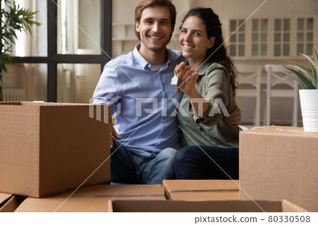 Bonding couple sit on couch holding keys celebrate moving day 80330508