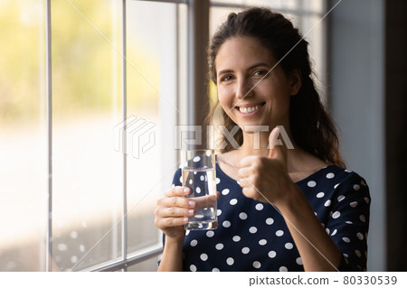 Happy Hispanic woman drinking fresh water, holding transparent glass 80330539