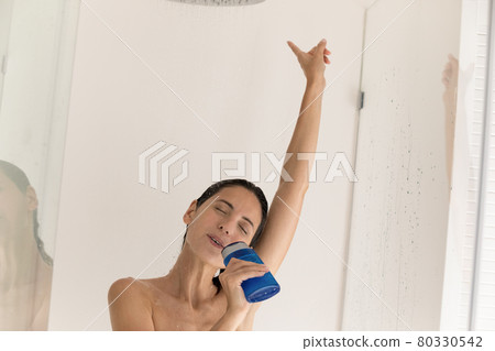 Carefree millennial latin lady singing popular song in bathroom relaxing 80330542
