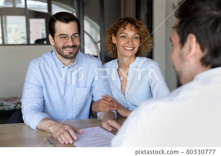 Happy young couple listening to manager at meeting in office Happy young couple listening to manager at meeting in office 80330777
