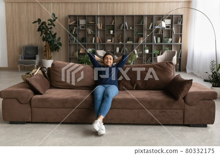 Calm Indian woman relax on sofa breathe fresh air Calm Indian woman relax on sofa breathe fresh air 80332175