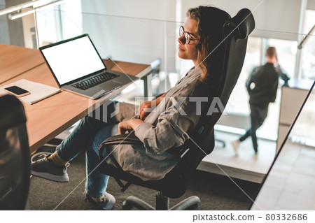 Woman sitting in the modern office using laptop Woman sitting in the modern office using laptop 80332686