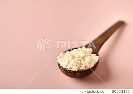 Hazelnut flour in wooden brown spoon on pink powder background Hazelnut flour in wooden brown spoon on pink powder background 80333331