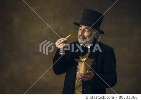 Handsome elderly gray-haired man, gentleman, aristocrat or actor eating fast food isolated on dark vintage background. Retro style, comparison of eras concept. Handsome elderly gray-haired man, gentleman, aristocrat or actor eating fast food isolated on dark vintage background. Retro style, comparison of eras concept. 80333366