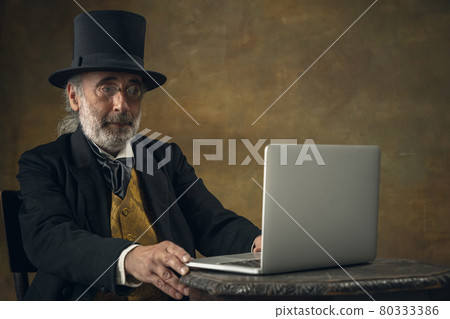 Half-length retro portrait of sad elderly gray-haired man, gentleman, aristocrat or actor isolated on dark vintage background. Retro style, comparison of eras concept. Half-length retro portrait of sad elderly gray-haired man, gentleman, aristocrat or actor isolated on dark vintage background. Retro style, comparison of eras concept. 80333386