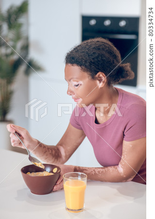 Dark-skinned young woman having breakfast at home Dark-skinned young woman having breakfast at home 80334734