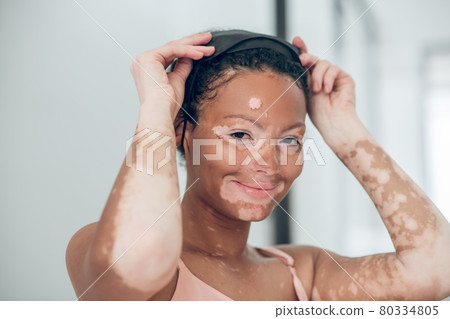 Young mulatta putting on a mask for sleep Young mulatta putting on a mask for sleep 80334805