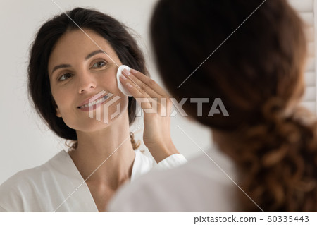 Young hispanic female remove makeup by mirror using sponge 80335443