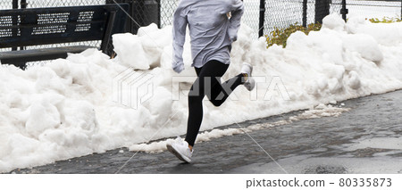Young girl running fast in a parking lot with snow and ice 80335873