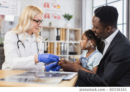 Man holding daughter while doctor checking saturation Man holding daughter while doctor checking saturation 80336161