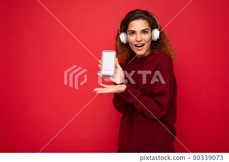 Shot of attractive amazed positive young brunet curly woman wearing dark red sweater isolated on red Shot of attractive amazed positive young brunet curly woman wearing dark red sweater isolated on red 80339073