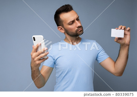 Portrait of concentrated Handsome man wearing everyday clothes isolated on background wall holding Portrait of concentrated Handsome man wearing everyday clothes isolated on background wall holding 80339075