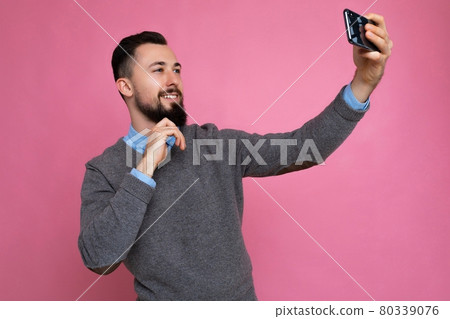 Handsome young man wearing casual stylish clothes standing isolated over background wall holding 80339076