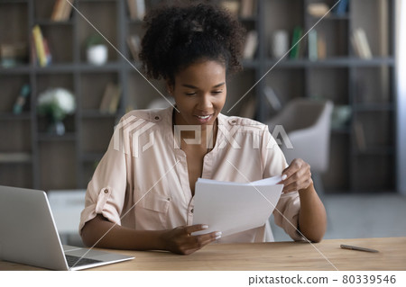 Smiling African American woman working with documents, sitting at desk Smiling African American woman working with documents, sitting at desk 80339546