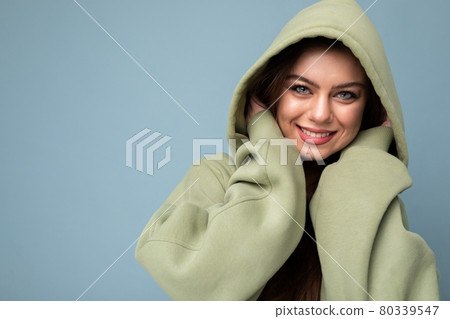 Portrait of attractive young caucasian smiling brunette woman model in trendy khaki hoodie and Portrait of attractive young caucasian smiling brunette woman model in trendy khaki hoodie and 80339547