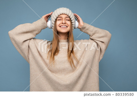 Photo of sexy beautiful happy smiling young blonde woman wearing beige winter sweater and hat Photo of sexy beautiful happy smiling young blonde woman wearing beige winter sweater and hat 80339580