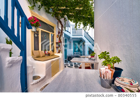 Traditional narrow cobbled streets, beautiful lanes of Greek island towns. Whitewashed houses, cafes, tables, chairs, stairs, doors. Mykonos, Greece 80340555
