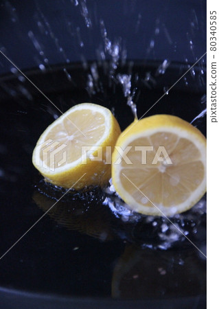 Lemons splashing into water on dark background Lemons splashing into water on dark background 80340585