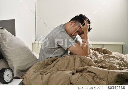 Depressed young Asian man sitting in bed cannot sleep from insomnia Depressed young Asian man sitting in bed cannot sleep from insomnia 80340688
