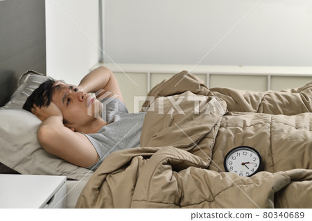 Depressed young Asian man lying in bed cannot sleep from insomnia Depressed young Asian man lying in bed cannot sleep from insomnia 80340689