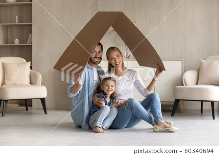 Happy family with adorable little daughter sitting under cardboard roof 80340694