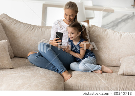 Happy mother with adorable little daughter using smartphone together 80340718