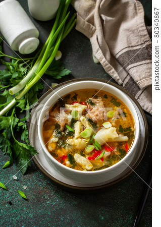 Hot delicious beef soup. Homemade soup with meat, vegetables and gnocchi on a dark stone background. Copy space. 80340867