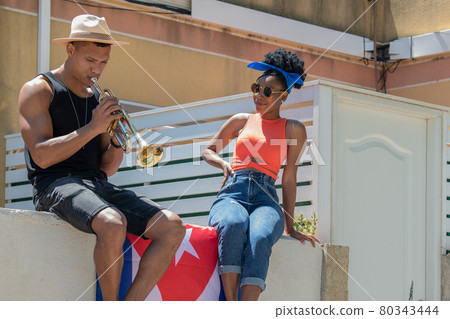 Latina woman watching a latino man playing a trumpet: Selective focus. Music and diversity concept. 80343444