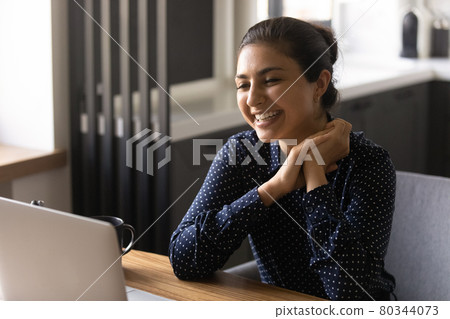 Happy Indian female employee working at laptop from home 80344073