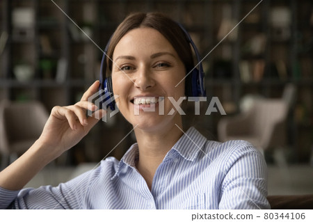 Young 30s woman in wireless headphones holding video call conversation. 80344106